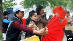 Vietnamese women perform fan dancing along the shores of Hoan Kiem Lake in Hanoi, Vietnam.