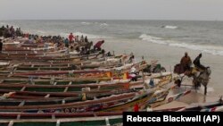FILE: A horse cart drives through the water past fishing boats lining an oceanside beach, in Saint-Louis, Senegal, Sunday, May 19, 2013.