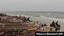 Une charrette à cheval roule dans l'eau le long de bateaux de pêche bordant une plage au bord de l'océan, à Saint-Louis, Sénégal, le dimanche 19 mai 2013. (AP Photo / Rebecca Blackwell)