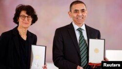 German scientists, CEOs and founders of BioNTech, Ozlem Tureci and Ugur Sahin pose with the Federal Cross of Merit awarded to them by German President Frank-Walter Steinmeier, on March 19, 2021. (Odd Andersen/Pool via REUTERS)