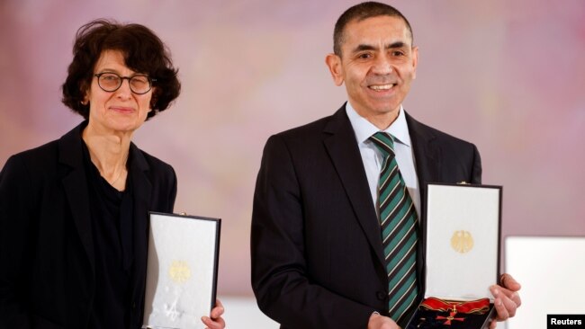 German scientists, CEOs and founders of BioNTech, Ozlem Tureci and Ugur Sahin pose with the Federal Cross of Merit awarded to them by German President Frank-Walter Steinmeier, on March 19, 2021. (Odd Andersen/Pool via REUTERS)