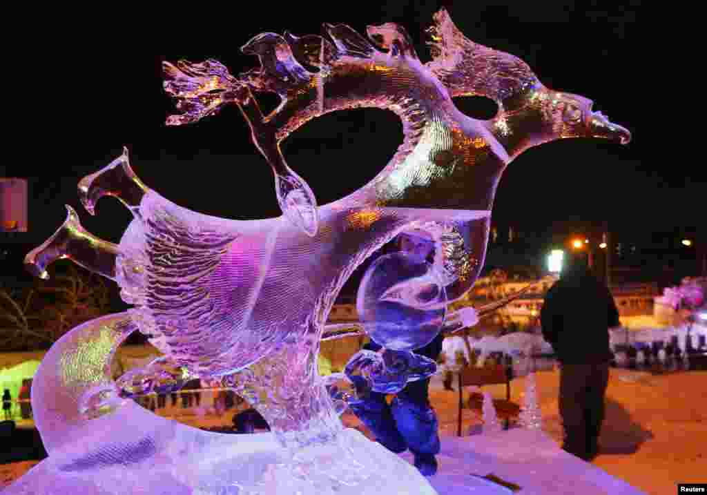 Alexander Baranmaa (C), from the town of Kyzyl in the Republic of Tuva, finishes working on an ice sculpture called &quot;Macro Space&quot; during the international festival of snow and ice sculptures The Magical Ice of Siberia in Krasnoyarsk, Siberia, Jan 17. 2015.