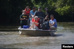People ride a boat though flood water after being evacuated from the rising water following Hurricane Harvey in a neighborhood west of Houston, Texas