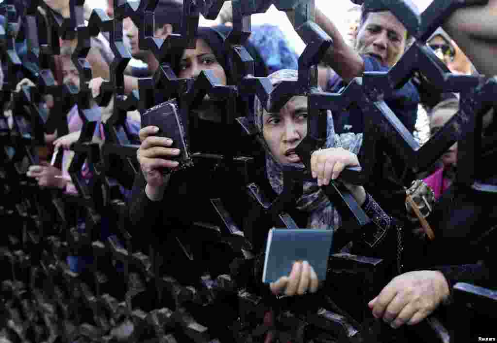 Palestinians standing behind the gate of Rafah crossing in the southern Gaza Strip hold their passports as they try to cross into Egypt. At least 74 Palestinians, most of them civilians, have been killed in Israel&#39;s Gaza offensive, Palestinian officials said.