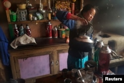 FILE - A Nepalese woman prepares tea in a refuge for mountaineers in the Khumbu Valley in the Everest region of Nepal, April 14, 2016.