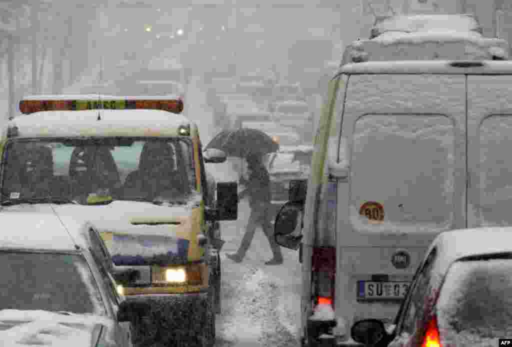 Một người đi bộ băng qua đường xe chạy phủ đầy tuyết trong thành phố Belgrade, Serbia, 3 tháng 2, 2012. (AP)