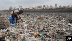 Seorang pria mengumpulkan plastik dan bahan-bahan yang bisa di daur ulang dari pantai Laut Arabia yang dipenuhi sampah kantong plastik dan sampah lainnya, di Mumbai, India, 4 Juni 2018.