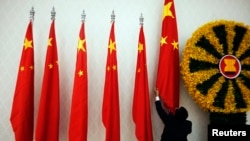 រូប​ឯកសារ៖ មន្ត្រី​ម្នាក់​រៀប​ចំ​ទង់​ជាតិ​ចិន​ មុន​ពេល​​លោក​នាយករដ្ឋមន្ត្រី​ចិន Wen Jiabao មក​ចូលរួម​កិច្ច​ប្រជុំ​កំពូល​អាស៊ាន និង​អាស៊ី​ខាង​កើត នៅ​រាជធានី​ភ្នំពេញ​កាល​ពី​ខែ​វិច្ឆិកា ឆ្នំា២០១២។ (REUTERS/Damir Sagolj)