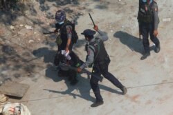 Riot police officers hold down a protester as they disperse demonstrators in Tharkata Township on the outskirts of Yangon, Myanmar, March 6, 2021.