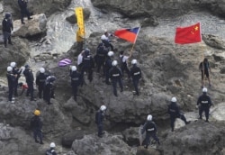 FILE - Activists holding Chinese and Taiwanese flags are arrested by Japanese police officers after landing on Uotsuri Island, one of the islands of Senkaku in Japanese and Diaoyu in Chinese, in East China Sea, Aug. 15, 2012.