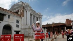 A foreign delegate photographs damaged buildings at the Basantapur Durbar Square heritage site in Kathmandu, Nepal, June 24, 2015.