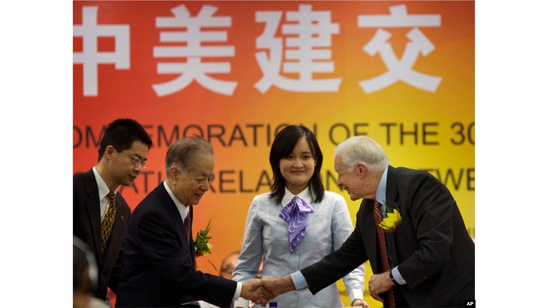 资料照:美国前总统卡特(右)在北京出席纪念美中建交30周年的研讨会上与时任中国副总理钱其琛(左二)握手。( 2009年1月12日)