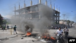 ARCHIVO: Motociclistas pasan por entre los neumáticos quemados en una calle de Puerto Príncipe, la capital de Haití, durante un día de levantamiento contra el primer ministro haitiano Hariel Henry, el 18 de enero de 2024.