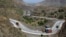 FILE - Afghanistan-bound trucks pass through a valley while moving toward the Torkham border crossing in Torkham, Pakistan, Saturday, June 18, 2016. 