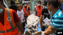 The sister (2nd left) of a protester shot dead with live rounds during an anti-coup protest watches as his body is being moved into a makeshift medical center in Mandalay, Myanmar, March 13, 2021.