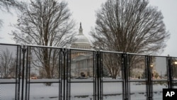 Security fencing surrounds Capitol Hill as snow blankets the region ahead of a joint session of Congress to certify the votes from the Electoral College in the presidential election, in Washington, Monday, Jan. 6, 2025. (AP Photo/J. Scott Applewhite)