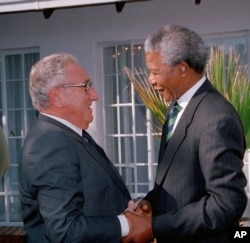 FILE - Former U.S. Secretary of State Henry Kissinger, left, and ANC president Nelson Mandela shake hands during their meeting in Johannesburg, South Africa, on April 13, 1994.