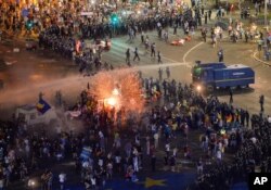 FILE - A tear gas canister explodes as riot police charge using canon to clear the square during protests outside the government headquarters in Bucharest, Romania, Aug.10, 2018.