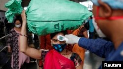 Petugas memeriksa suhu tubuh para penumpang di stasiun kereta Mumbai, di tengah lonjakan infeksi COVID-19 di India, Rabu (17/3). 