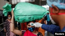 A health worker checks the temperature of a passenger, amid the spread of the coronavirus disease, at a railway station in Mumbai, India, March 17, 2021.