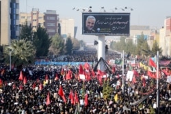 FILE - Iranian people attend a funeral procession and burial for Iranian Major-General Qassem Soleimani, head of the elite Quds Force, who was killed in an air strike at Baghdad airport, at his hometown in Kerman, Iran, Jan. 7, 2020.