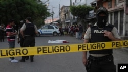 ARCHIVO - La policía custodia la escena del crimen donde el cuerpo de un hombre, asesinado en circunstancias desconocidas, yace cubierto en una calle de Durán, Ecuador, el viernes 21 de julio de 2023.