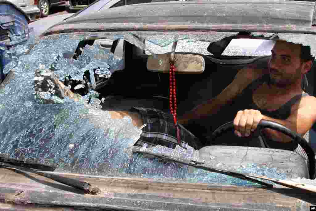 A Lebanese man breaks the glass of his damaged vehicle near the Bilal bin Rabbah mosque in the southern port city of Sidon, Lebanon. 