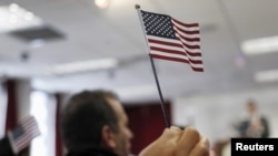 Una bandera de pequeño formato es alzada en una ceremonia de naturalización en una oficina de Ciudadanía en Nueva York, en noviembre de 2015.