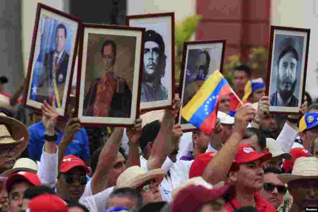 Cuban doctors hold up framed pictures (L-R) of late president Hugo Chavez, Venezuela&#39;s National hero Simon Bolivar, Ernesto &#39;Che&#39; Guevara, Cuban national hero Jose Marti and Fidel Castro during a march of farmers in support of Venezuelan President Nicolas Maduro, Caracas, Feb. 26, 2014. 