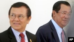 Cambodia's Prime Minister Hun Sen, right, walks with opposition Cambodia Rescue Party Deputy President Kem Sokha, left, during a break at National Assembly in Phnom Penh, Cambodia, Wednesday, Dec. 7, 2016. 