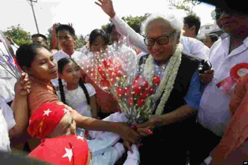 Win Tin, center, a senior leader of Myanmar opposition leader Aung San Suu Kyi's National League for Democracy (NLD) party, receives flowers from the party's members as he attends an opening ceremony of a branch office of the NLD party Tuesday, April 23, 