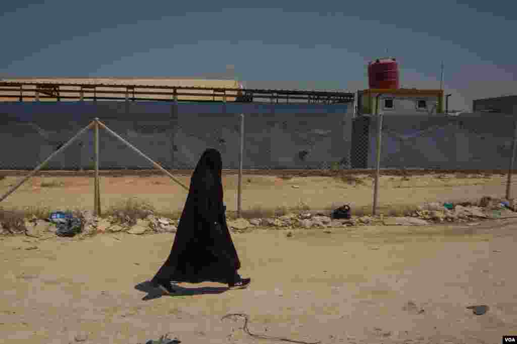 A woman walks by the entrance of the al-Hol Camp in northern Syria. More than 70,000 people who were living in IS-controlled areas are detained here, Aug. 26, 2019. (Yan Boechat/VOA)