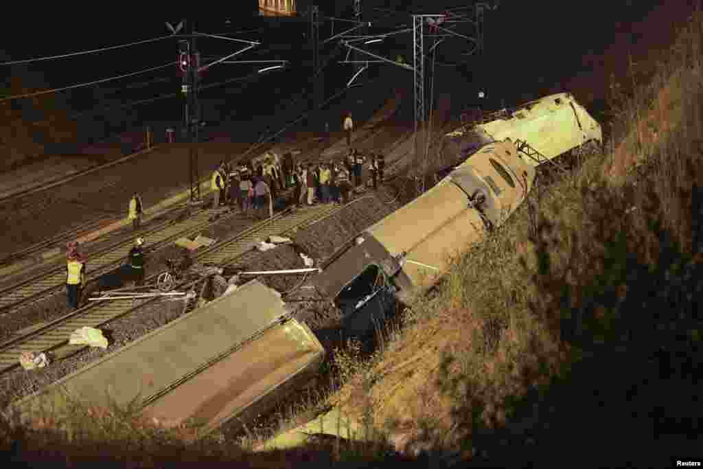Rescue workers and officials are seen amongst the wreckage of the train crash near Santiago de Compostela, northwestern Spain, early July 25, 2013.&nbsp;