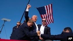 Le candidat républicain à la présidence et ancien président Donald Trump, est évacué par les services secrets après avoir été blessé lors d'un meeting de campagne, le 13 juillet 2024, à Butler, en Pennsylvanie (AP Photo/Evan Vucci).