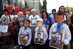 FILE - Relatives hold portraits of Ukrainian soldiers killed by Russian artillery near the village of Ilovaysk in eastern Ukraine, during a protests in front of the Russian Embassy in Kyiv, Ukraine, Aug.28, 2019.