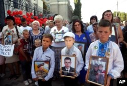 FILE - Relatives hold portraits of Ukrainian soldiers killed by Russian artillery near the village of Ilovaysk in eastern Ukraine, during a protests in front of the Russian Embassy in Kyiv, Ukraine, Aug.28, 2019.