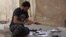 A Free Syrian Army member cleans his weapon on a street in Deir al-Zor, July 7, 2013.