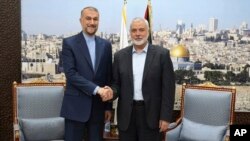 FILE - In this picture released by the Iranian Foreign Ministry, Iran's Foreign Minister Hossein Amirabdollahian, left, shakes hands with Hamas chief Ismail Haniyeh in Doha, Qatar, October 31, 2023.