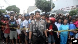 A policeman stands guard as residents watch the site of an explosion in front of a church in Solo, Central Java September 25, 2011.