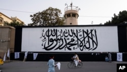 The iconic Taliban flag is painted on a wall outside the American embassy compound in Kabul, Sept. 11, 2021. 