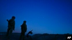 FILE - Russia-backed rebels are seen guarding territory after sunset near Donetsk, eastern Ukraine, Aug. 2, 2015.