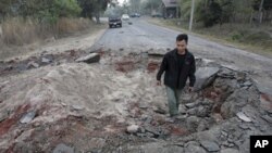 A Thai man walks though a bomb crater near Sisaket, Thailand, near the border with Cambodia, Monday, Feb. 7, 2011. Troops of Cambodia and Thailand continue to clash near the 11th century Preah Vihear temple.