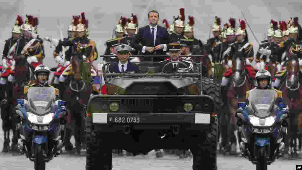 Le nouveau président français Emmanuel Macron monte dans un véhicule militaire dans la parade à Paris, en France, le 14 mai 2017.
