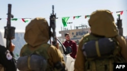 Hamas militants escort Israeli-Russian hostage Sasha Trupanov before handing him over to a Red Cross team in Khan Yunis, southern Gaza Strip, on Feb. 15, 2025, as part of the sixth hostage-prisoner exchange. 