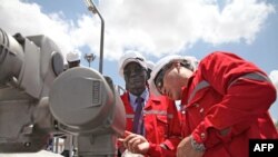 South Sudan's Minister for Petroleum and Mining Stephen Dhieu Dau (L) pushes a button to resume production at an oil field in South Sudan early this year.