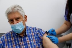 FILE PHOTO: An elderly person receives a dose of the Oxford/AstraZeneca COVID-19 vaccine at Cullimore Chemist, in Edgware, London, Britain, Jan. 14, 2021.
