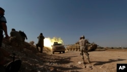 FILE - Free Syrian Army fighters fire from a tank during offensive to take control of al-Zaalana checkpoint in Wadi al-Deif military camp, southern Idlib countryside, July 9, 2014.