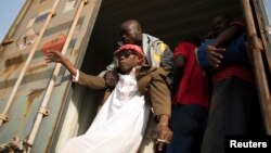 Un homme aide une personne aveugle à descendre d'un camion à la frontière du Cameroun et de la Centrafrique, le 8 mars 2014.