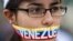 An anti-government demonstrator stands with a tri-colored ribbon covering her mouth that reads "Venezuela" during a protest in front of an office of the Organization of American States, OAS, in Caracas, Venezuela, Friday, March 21, 2014. 