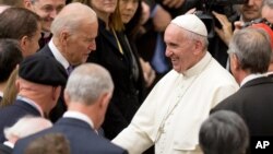 FILE - Pope Francis shakes hands with then U.S. Vice President Joe Biden as they take part in a conference being held at the Vatican, April 29, 2016. 